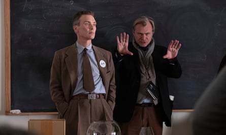 Two white men, one in front with hands in suit pants, the other gesturing behind him with both hands.