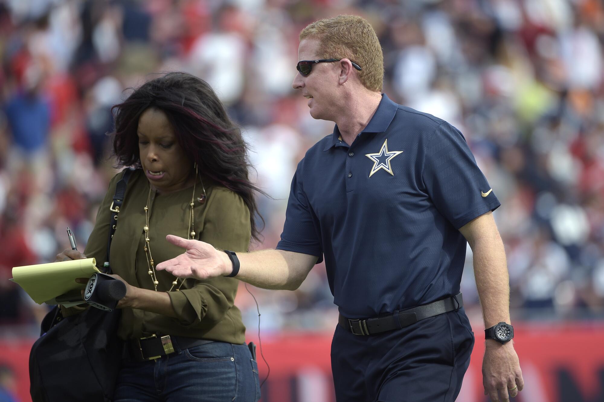 Fox Sports sideline reporter Pam Oliver writes in a notepad as she talks with Cowboys coach Jason Garrett during a game
