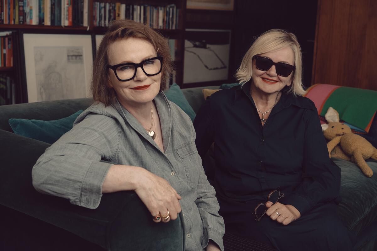 Two women sit on a couch for a portrait.