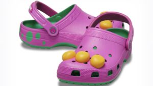 A pair of from Barney and Friends themed purple and green Crocs on display with one facing forward and the other sideways