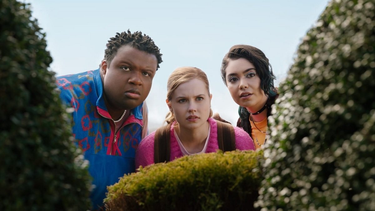 Damian, Cady, and Janis in Mean Girls (2024) look through bushes.