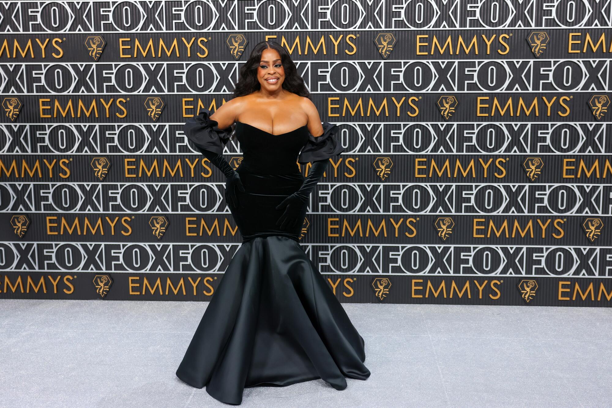 Niecy Nash-Betts wears a black dress on the Emmys red carpet.
