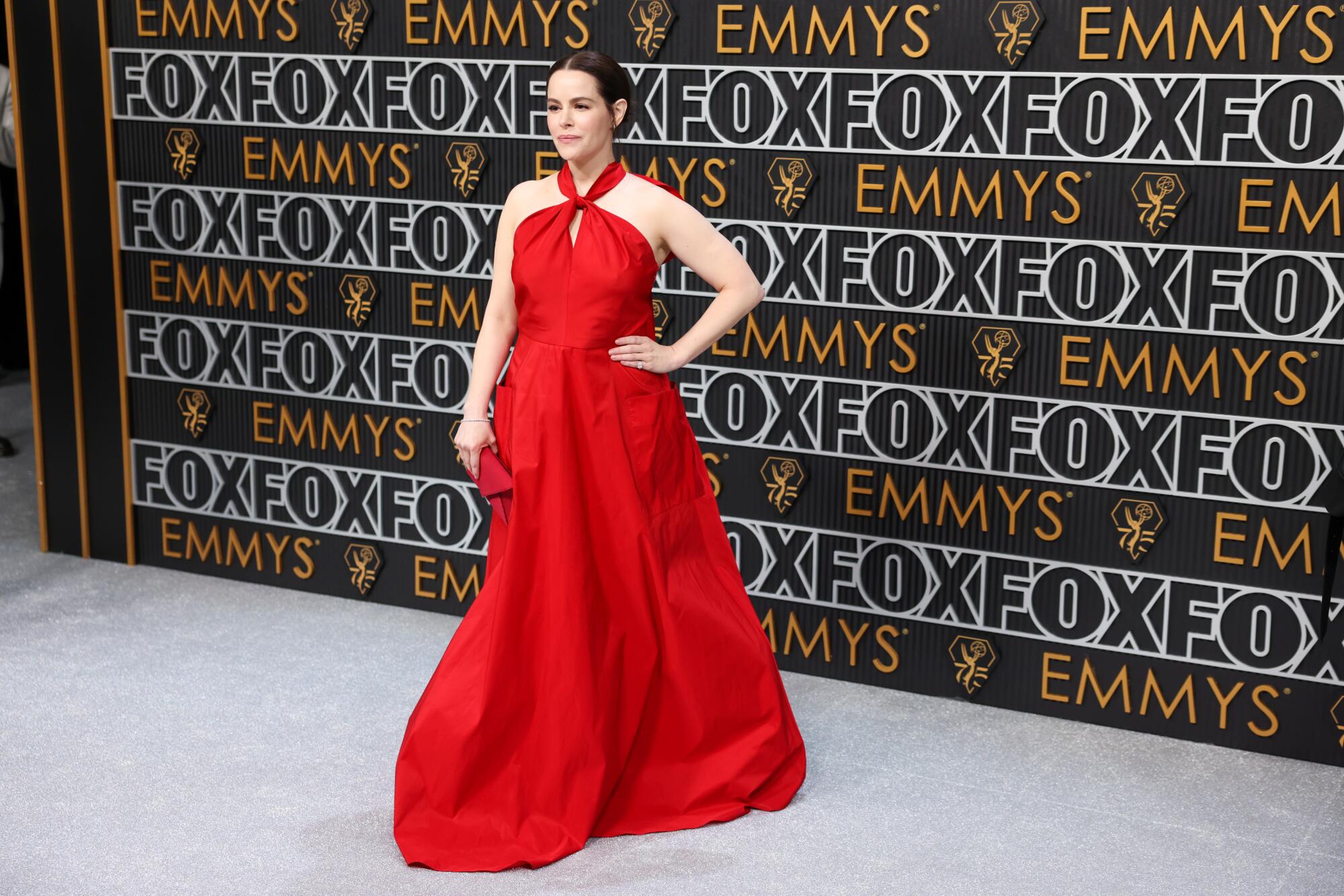 Emily Hampshire wears a red dress on the Emmys red carpet. 