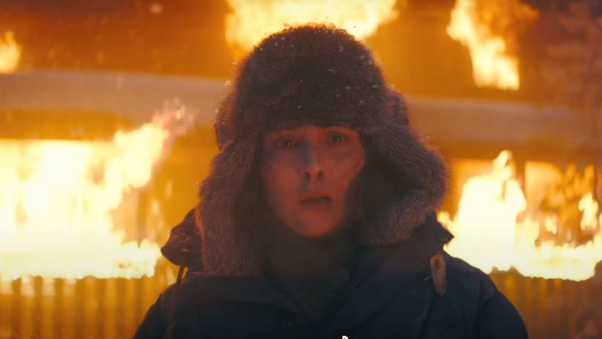a woman wears a fur coat and looks terrified in front of a burning building in constellation series trailer
