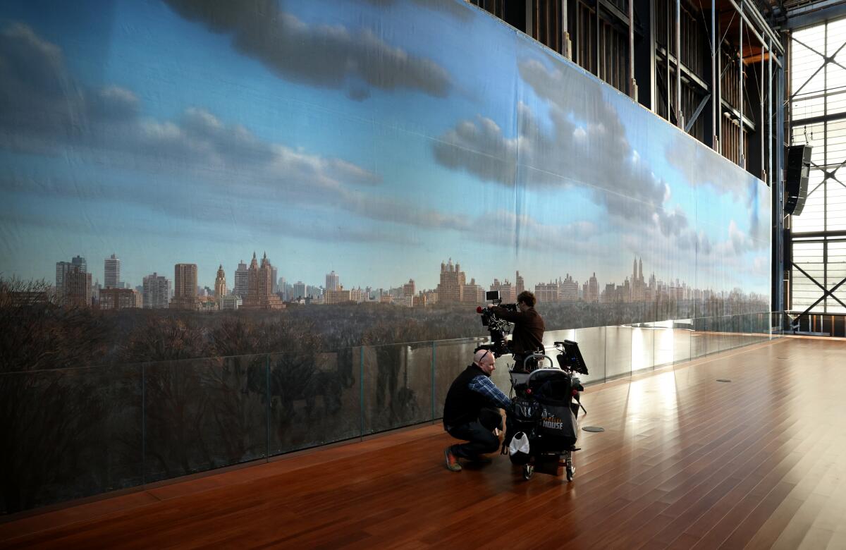 Video crew stands next to a backdrop of the New York City skyline