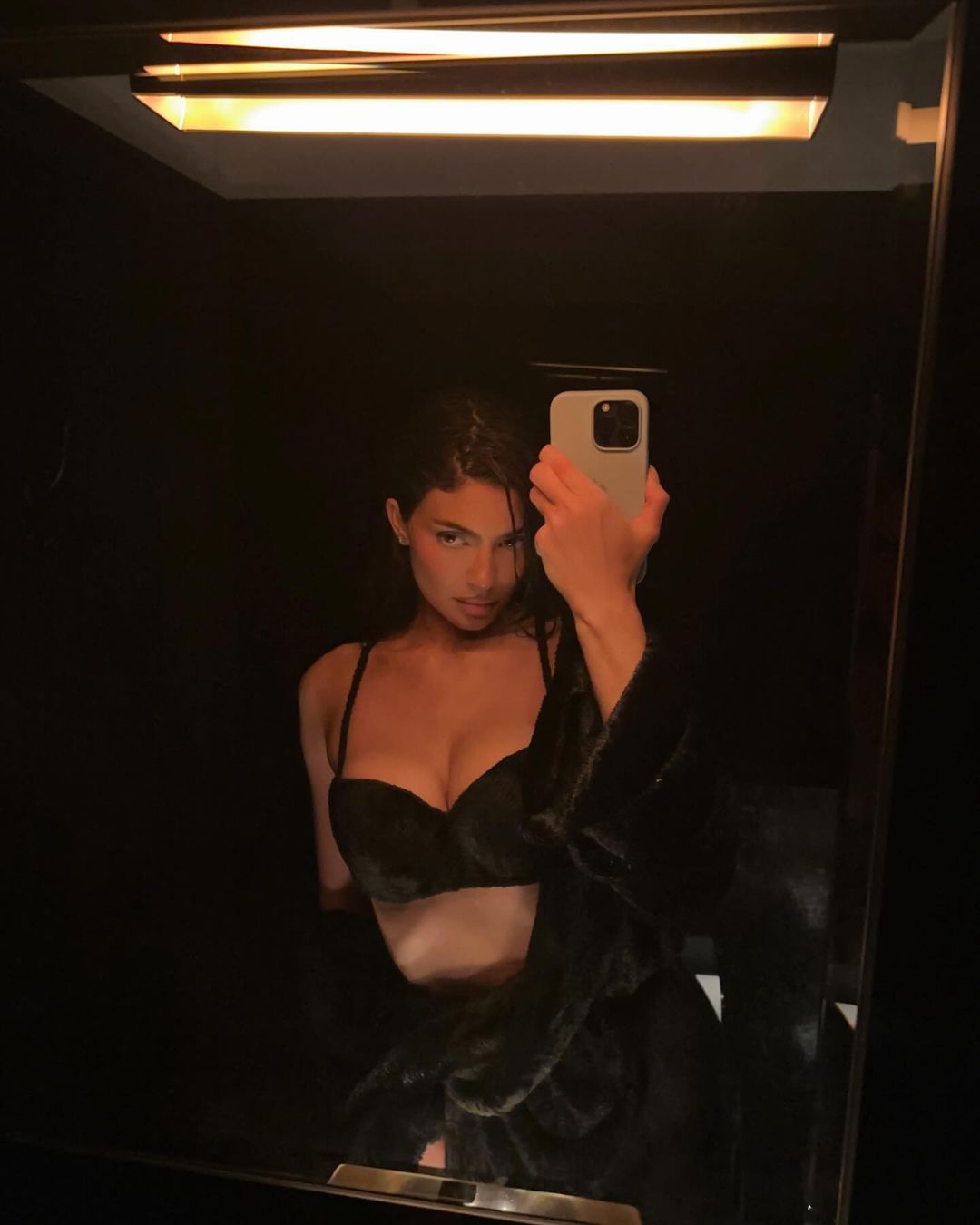 On Saturday, Kylie showed off her slim waist in a black velvet bra and high-slit skirt for a mirror selfie before a stroll around Paris
