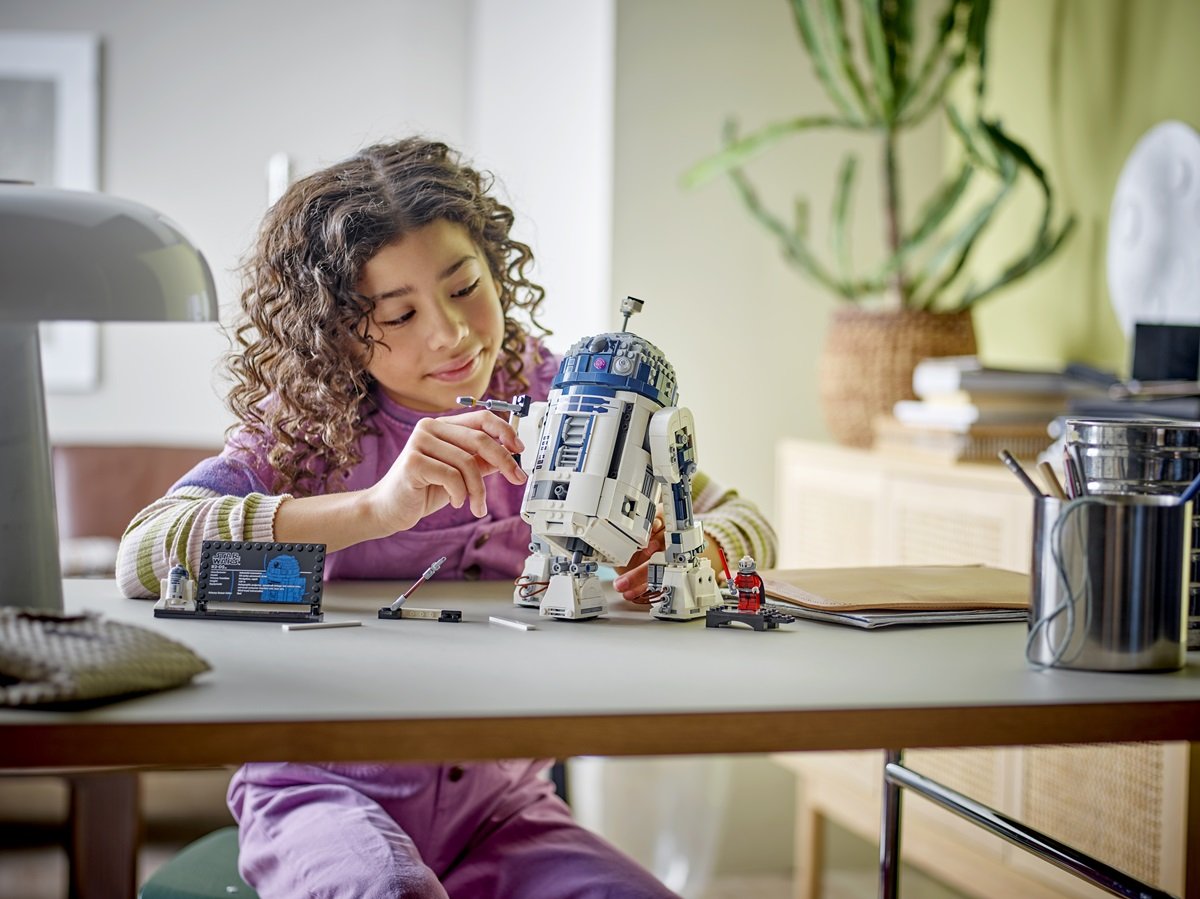 Child plays with LEGO 25th anniversary Star Wars R2-D2. 