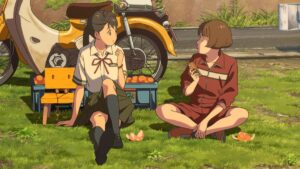 Suzume, in a school uniform, eating fruit on the side of a rural road with Chika, in a gym uniform.