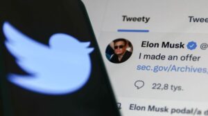 Elon Musk's Tweet displayed on a screen and Twitter logo displayed on a phone screen