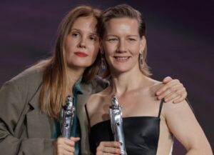 The director of Anatomy of a Fall, Justine Triet, with the film’s star, Sandra Hüller, holding awards.