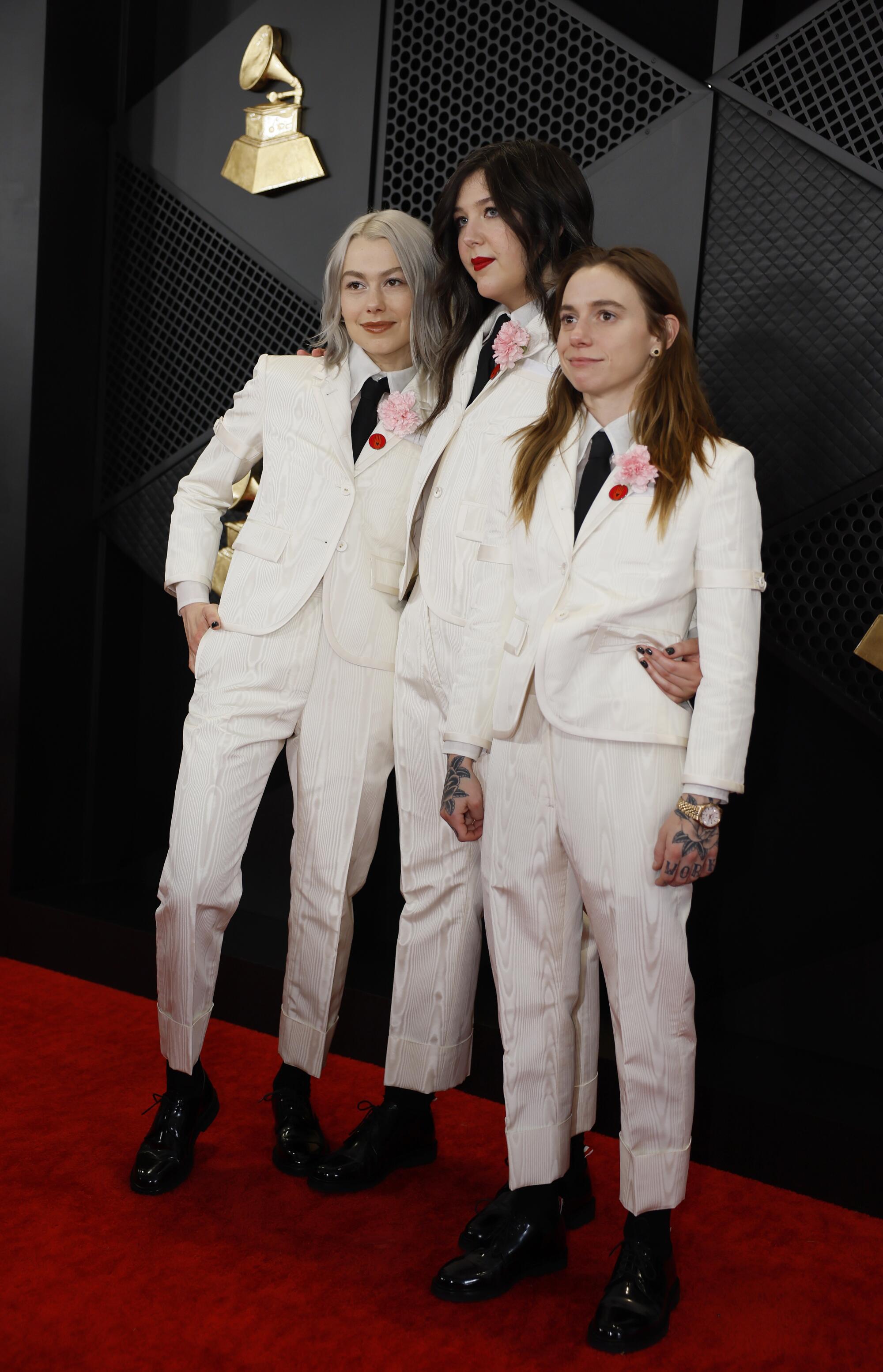 Three women in white suits with black ties