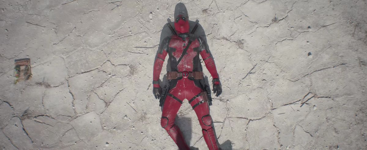 Deadpool faints on the desert ground next to a Secret Wars comic book in Deadpool &amp; Wolverine