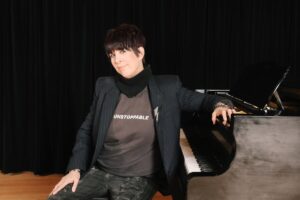 Songwriter Diane Warren sits at a piano for a portrait.