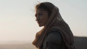 Zendaya as Chani with a hood on her head stands in the desert in Dune