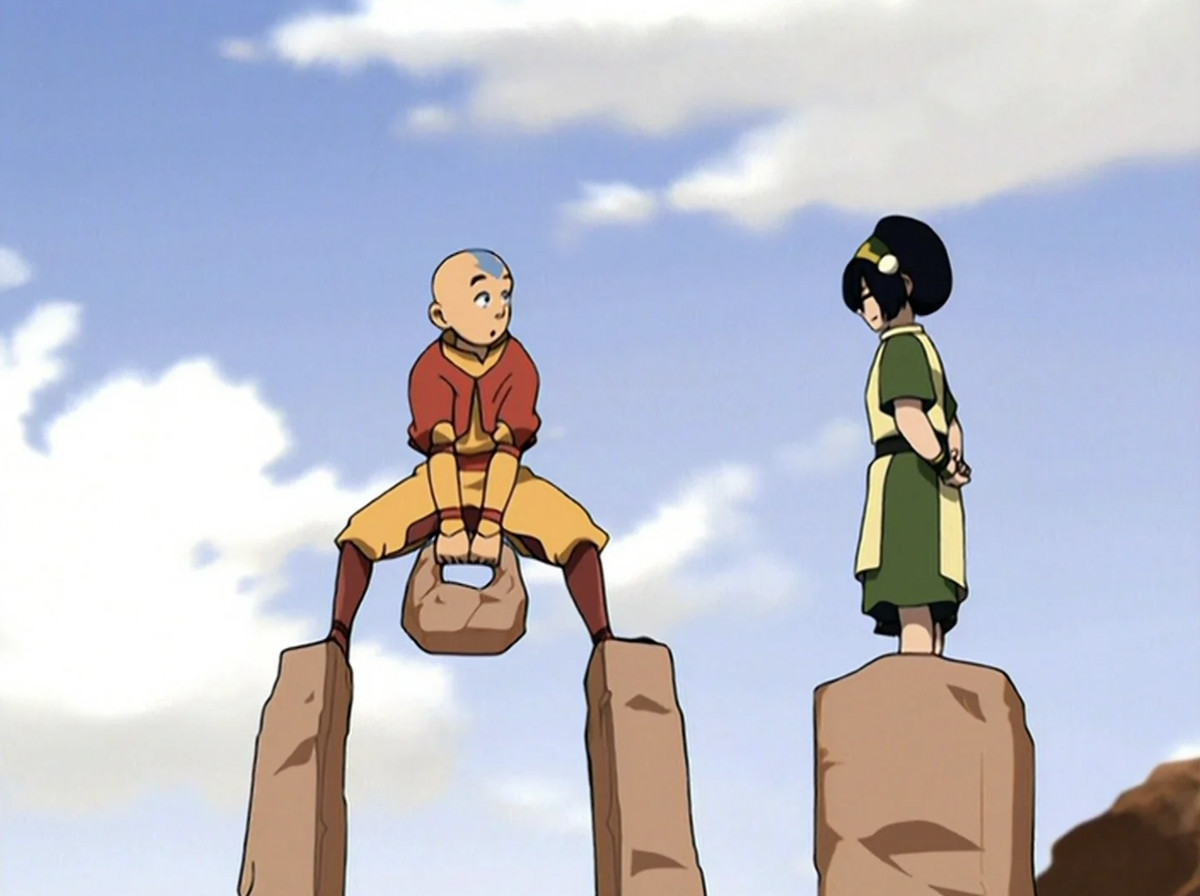Aang standing and holding a boulder on two pedestals while Toph stands on one instructing him