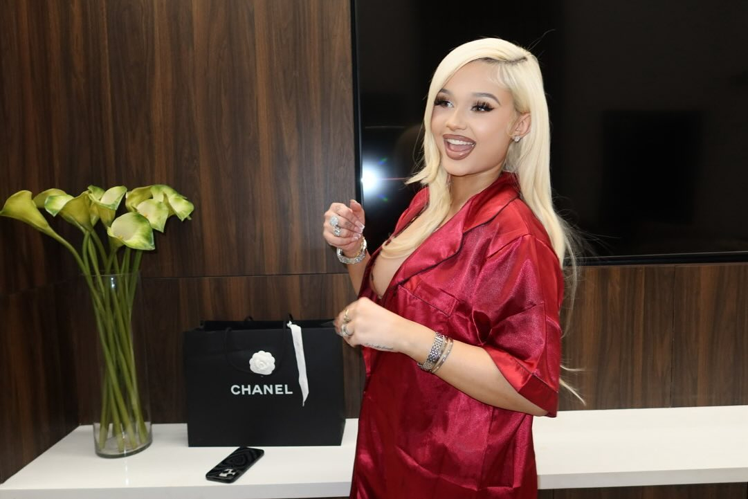 Alabama laughed as she posed next to a Chanel bag and flat-screen TV