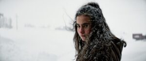 A young woman stands with snow in her dark hair.