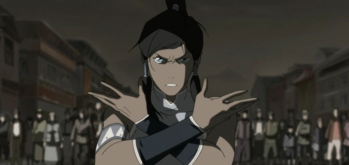 The Legend of Korra protagonist Korra stands in front of a crowd, arms crossed, staring into the camera