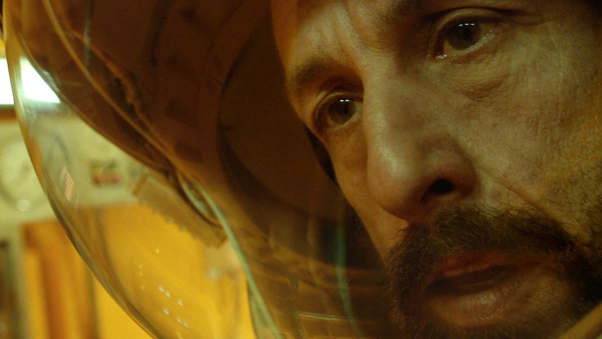 Adam Sandler with a beard in an astronaut helmet in Spaceman
