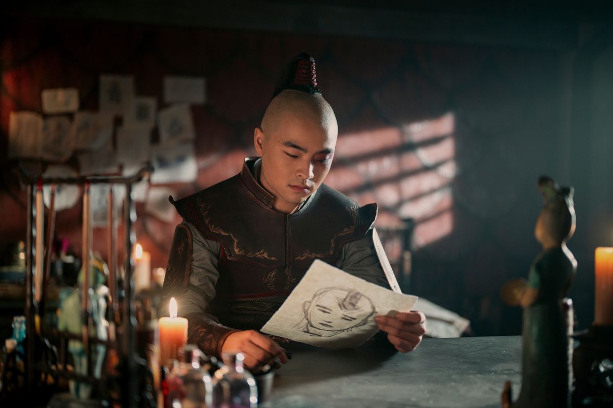 Zuko looking at his drawings, which include a sketch of Aang