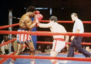 Actor Sylvester Stallone, as Rocky Balboa, punches actor Carl Weathers, as Apollo Creed, during a boxing match in a still from the film, 'Rocky,' directed by John G Avildson. (Photo by Hulton Archive/Getty Images)