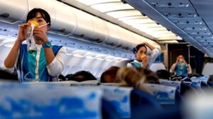 Flight attendants demonstrate the proper use of oxygen masks