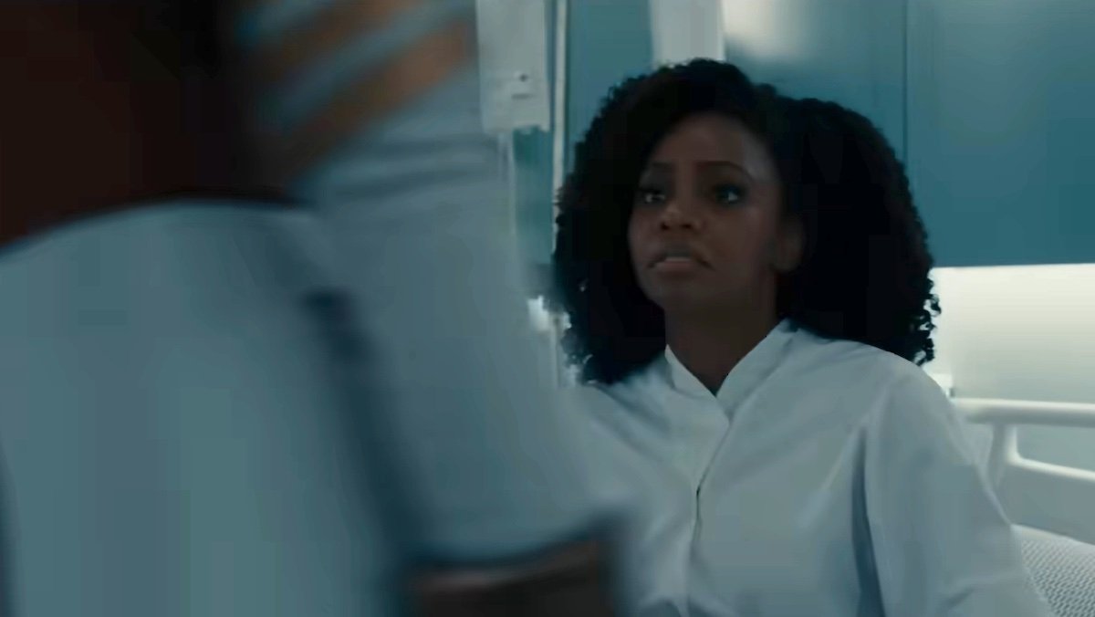 Monica Rambeau in a hospital bed looks surprised as someone walks by her in The Marvels