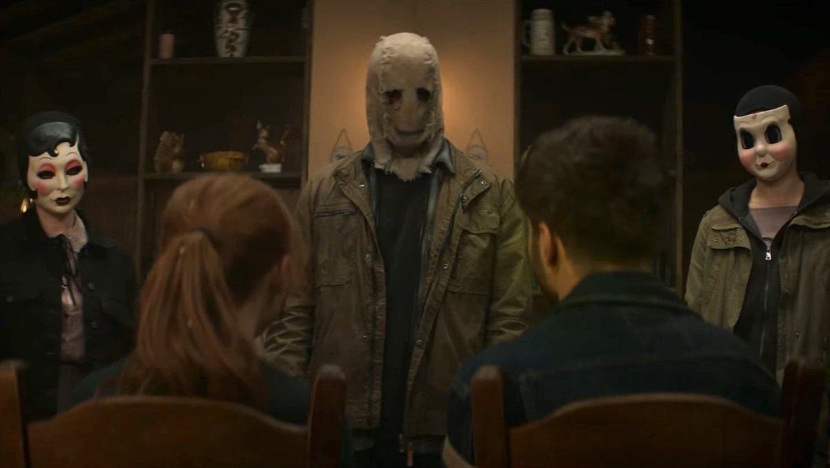 Three killers in masks stare at two people in chairs in The Strangers - Chapter 1