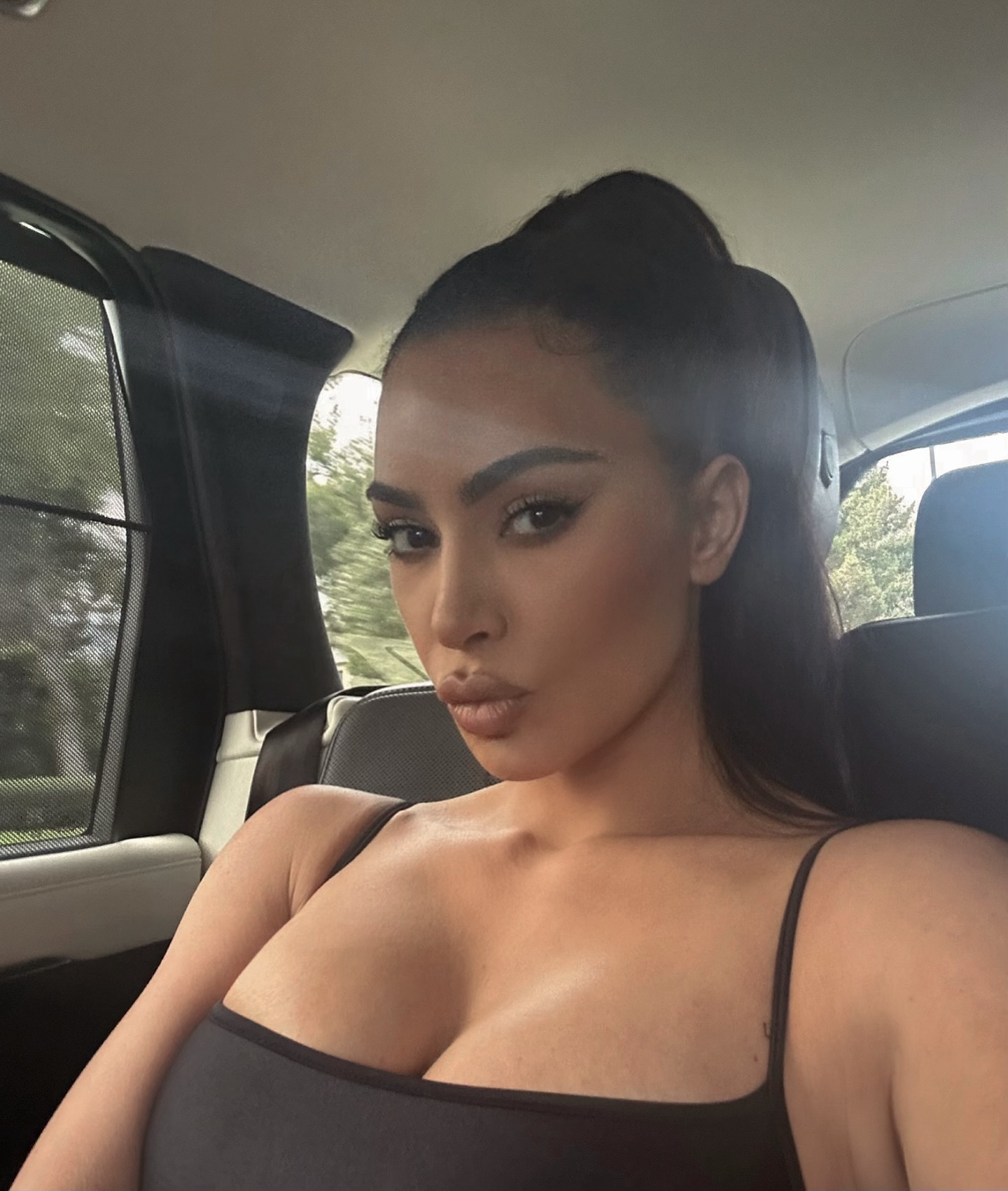 Kim nearly popped out of her tank top in the car selfie she posted on Instagram