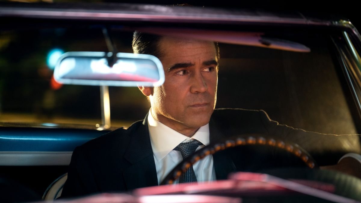 Colin Farrell sits behind the wheel of an old school car wearing a suit and tie in sugar trailer 