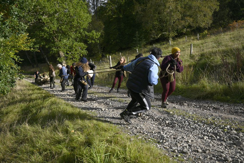 The cast of the Traitors season 2 pulling things up a hill during a mission