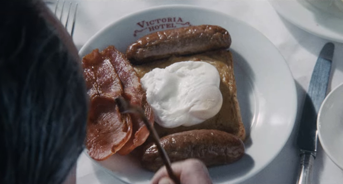 A close-up overhead shot of a Victoria Hotel plate of bacon, sausage, Welsh rarebit, and poached egg