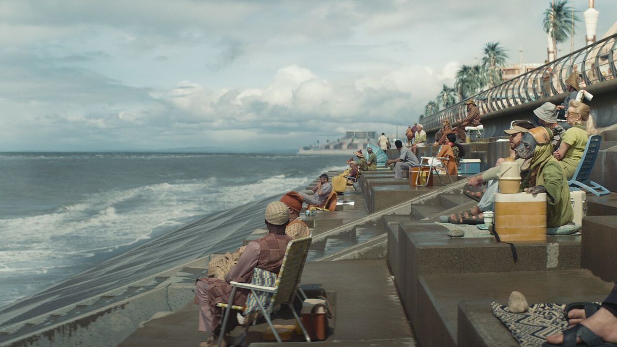 Beachgoers sit on concrete steps on the planet Niamos in Andor. 
