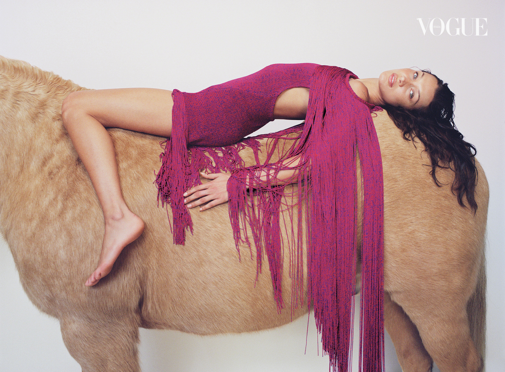 Bella wears a slashed purple dress as she drapes herself over a 'horse'