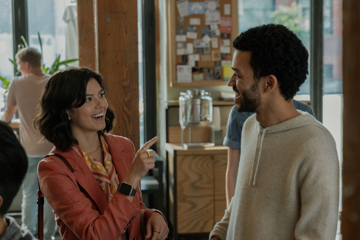 A smiling woman (An-Li Bogan) pointing at a smiling man (Justice Smith).