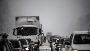 Cars and a bakery truck stuck on a highway during a snow storm.