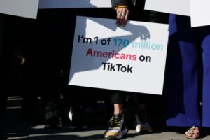Woman holds sign reading 'I'm 1 of 170 million Americans on TikTok.'
