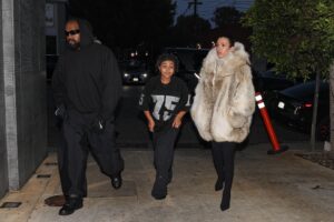 Bianca Censori covered up in a fur jacket while looking serious on an outing with Kanye and his kids