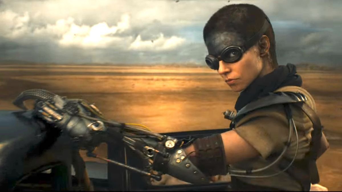Anya Taylor-Joy on a motorcycle with a shaved head and black on her forehead in Furiosa: A Mad Max Saga