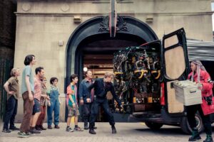 The cast of Ghostbusters: Frozen Empire stands outside the Ghostbusters firehouse collecting new proton packs