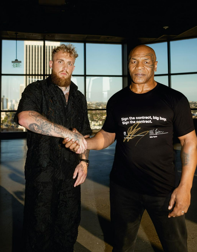 Jake Paul shaking hands with Mike Tyson after signing their fight deal