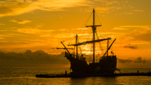 spanish galleon at sunrise with orange sky behind the ship