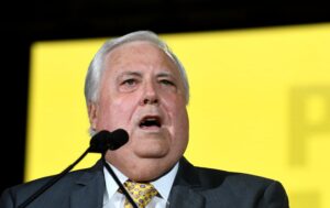 A man at a lectern speaks in front of a bright yellow backdrop