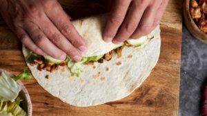 man rolling a burrito with his hands