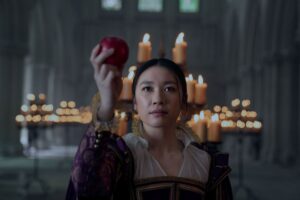 Jin Cheng (Jess Hong) holds up an apple in a medieval hall in 3 Body Problem.