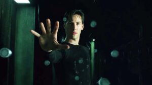 Keanu Reeves as Neo in The Matrix holds his hand up to stop bullets