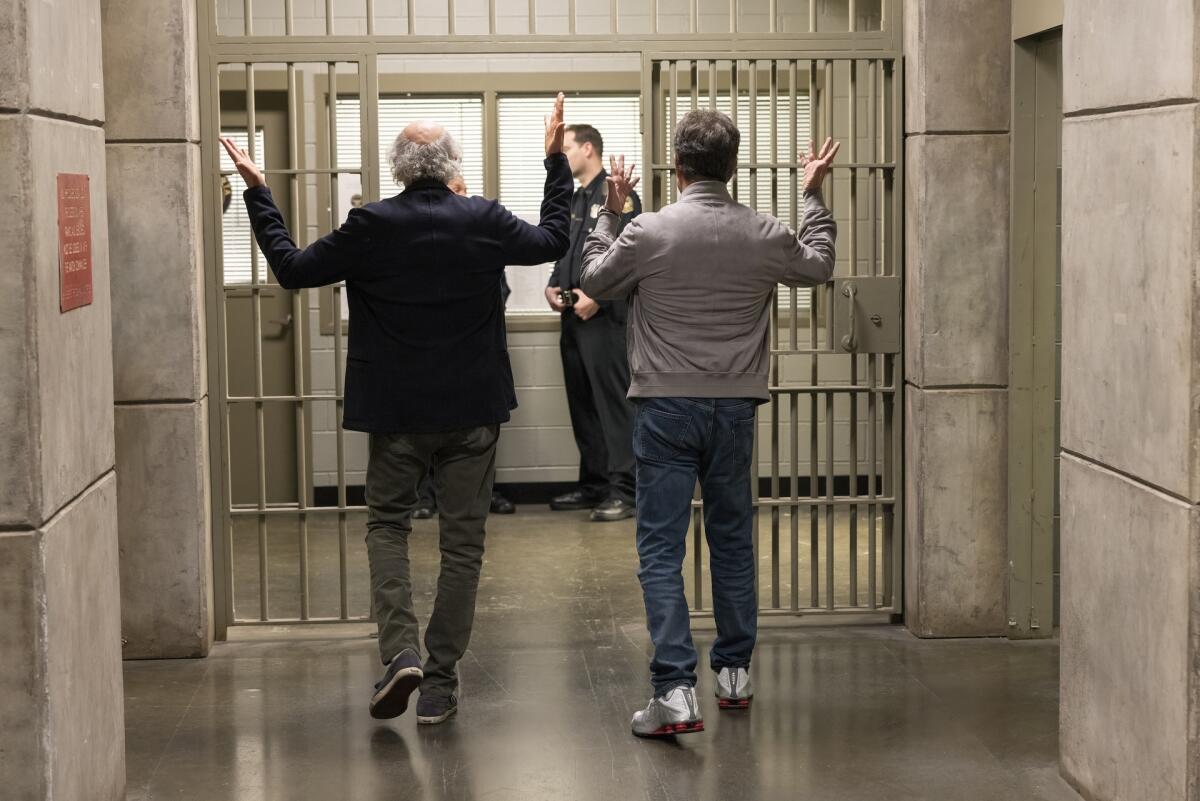 Two men seen from the back walking through the hallway of a jail.