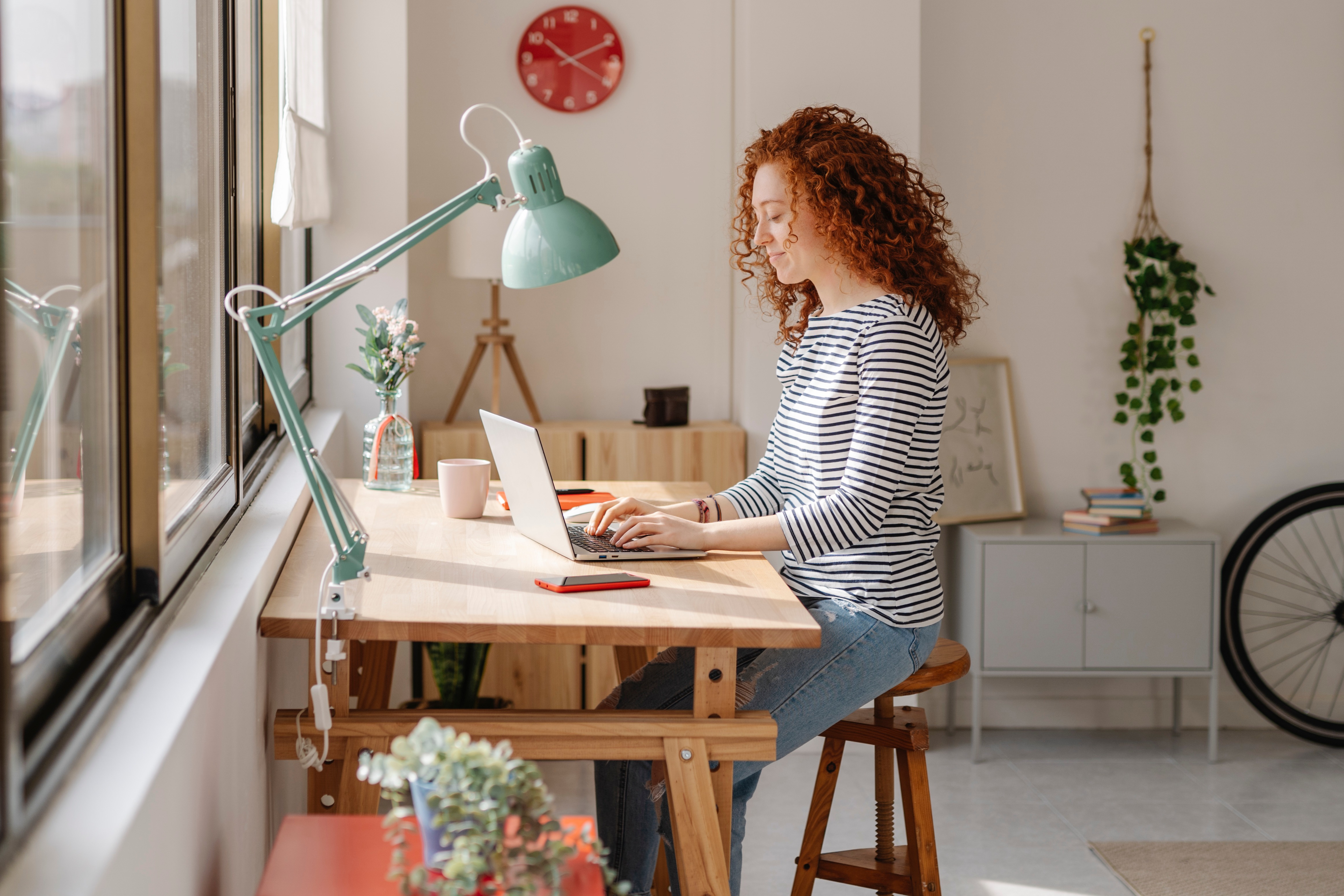 Woman sitting on a desk using a laptop computer while working from home. Business, freelance and home office concept.