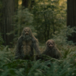 Two actors wear Sasquatch costumes in the woods.