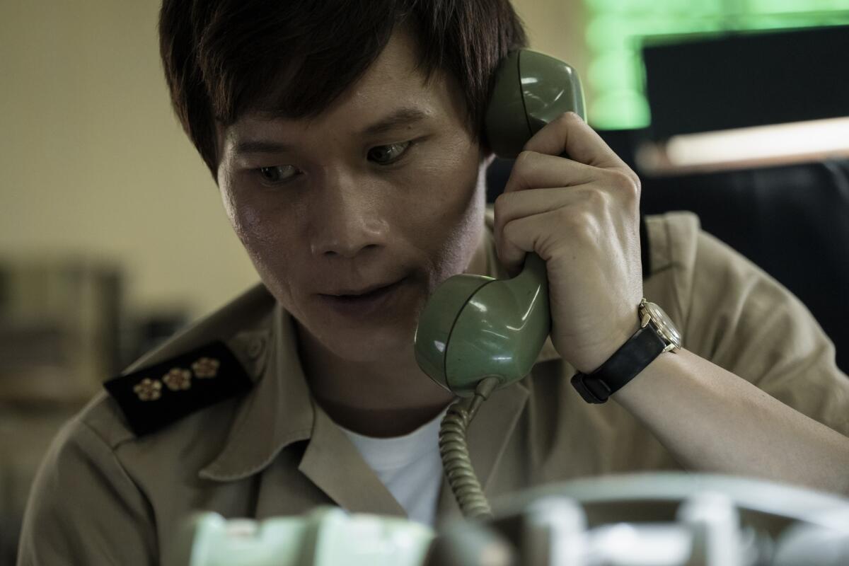 A man in a uniform hold a telephone receiver to his ear.